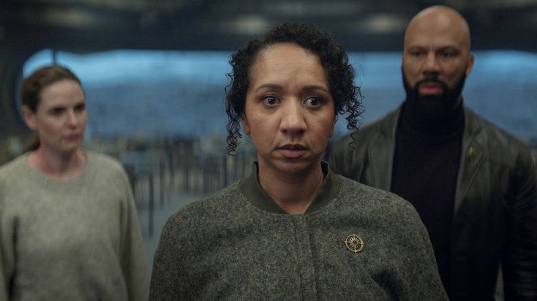 Camille looking horrified while Juliette and Robert stare at her in Silo