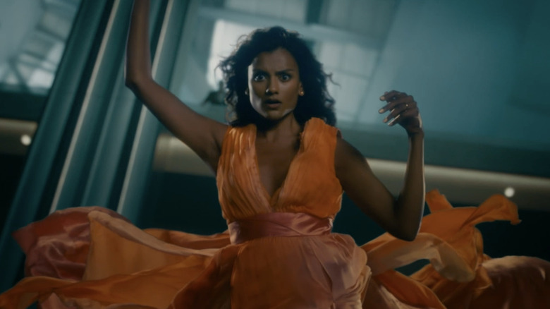 Simone Ashley's Mia is seen falling while wearing an orange dress in This Tempting Madness