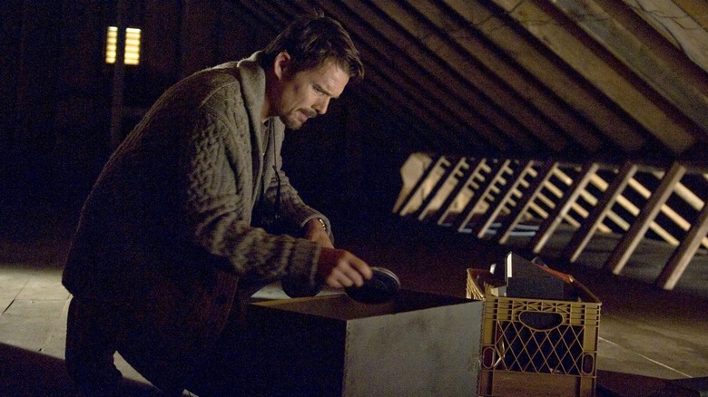 Ethan Hawke looking through a box of Super 8 film reels in Sinister