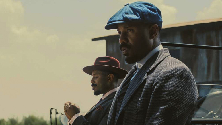 Michael B Jordan as Smoke and Stack outside the juke smoking a cigarette in Sinners