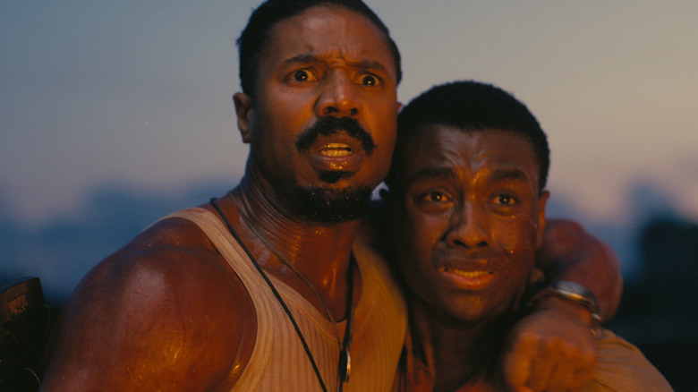Michael B. Jordan as Smoke and Miles Caton as Sammie Moore holding each other and looking terrified in Sinners