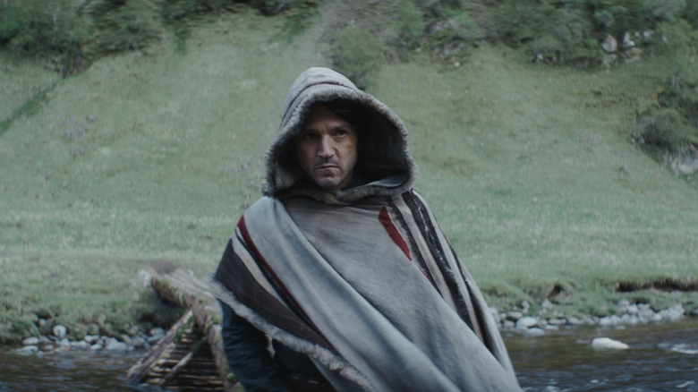 Cassian Andor in a hooded coat crosses the river on Aldani in Andor