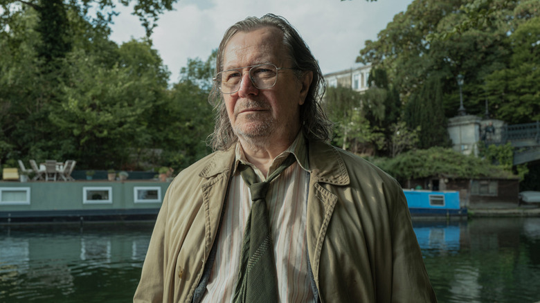 Gary Oldman's Jackson Lamb stands by a river in Slow Horses