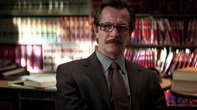 Gary Oldman's James Gordon sits in Harvey Dent's office in The Dark Knight