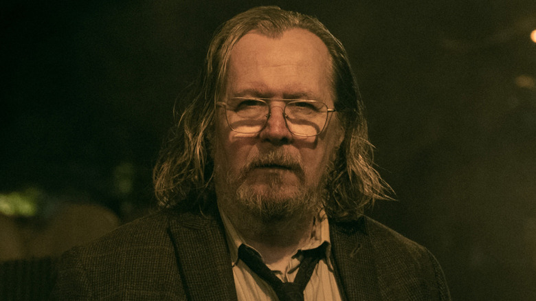 Gary Oldman as Jackson Lamb wearing a suit and standing in the middle of a darkened street at night in Slow Horses