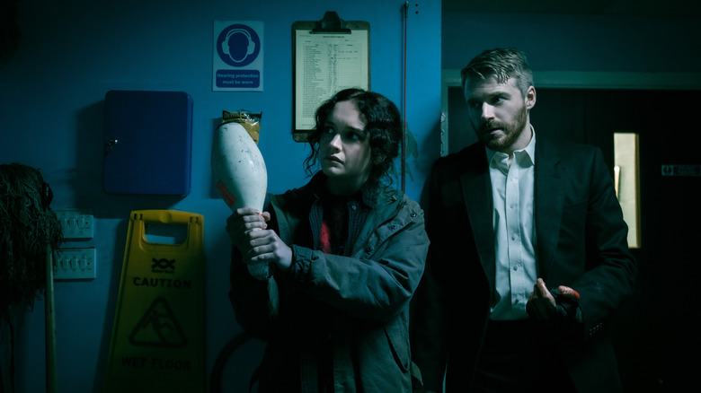 Olivia Cooke as Sid Baker holding up a bowling pin as a weapon next to Jack Lowden as River Cartwright in Slow Horses