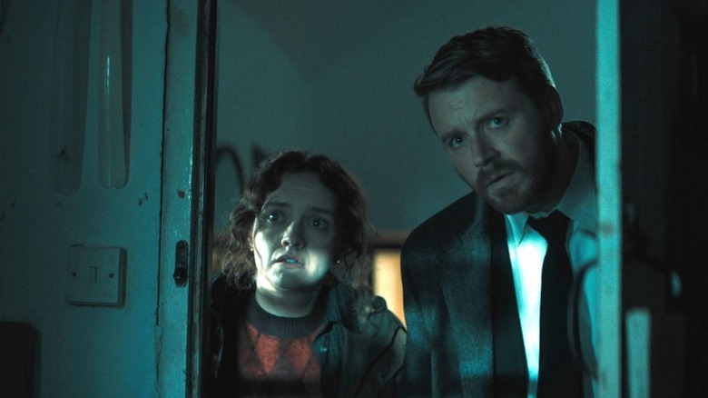 River and Sid standing next to each other in a dark room, looking at something off camera in Slow Horses Season 6