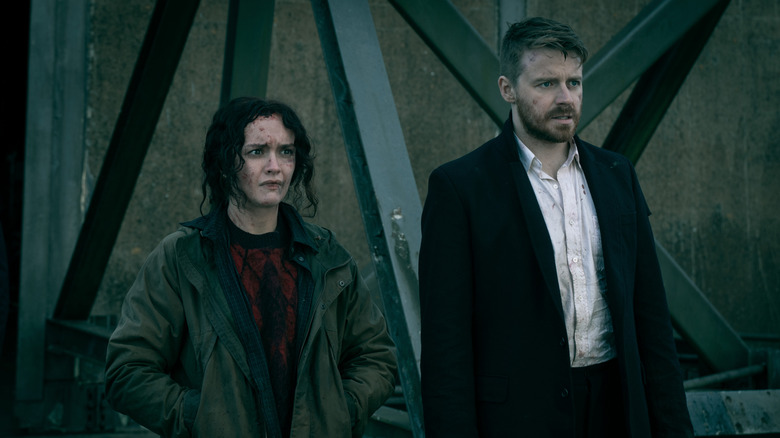 Olivia Cooke's Sidonie Baker stands outside an aircraft hanger next to Jack Lowden's River Cartwright in Slow Horses