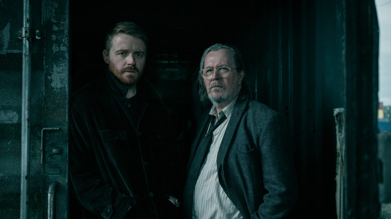 Gary Oldman's Jackson Lamb stands next to Jack Lowden's River Cartwright in the door of a shipping container in Slow Horses