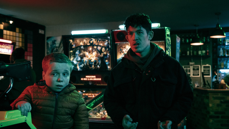 Christopher Chung's Roddy Ho stands next to Lenny Rush's Reece Nesmith in an arcade in Slow Horses