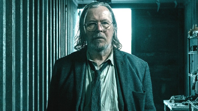 Gary Oldman as Jackson Lamb standing in a burned-out cargo container in Slow Horses