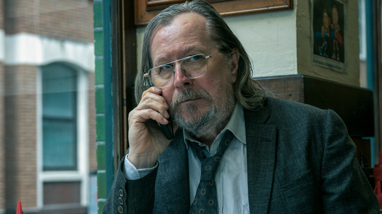 Gary Oldman as Jackson Lamb sitting at a café and making a call in Slow Horses