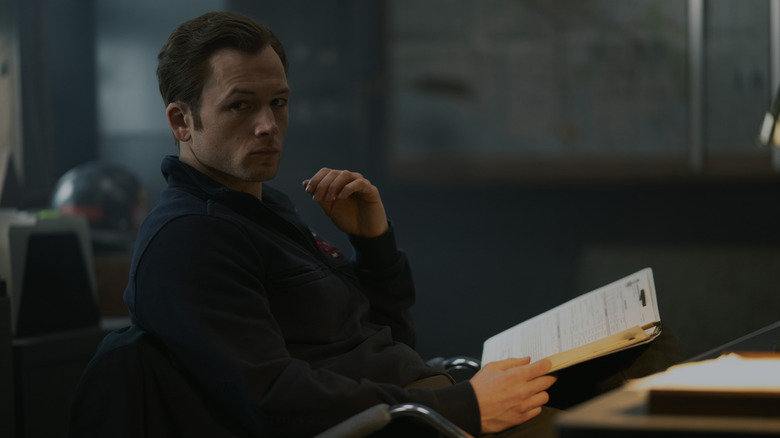 Taron Egerton peruses a file as Dave Gudsen in Smoke