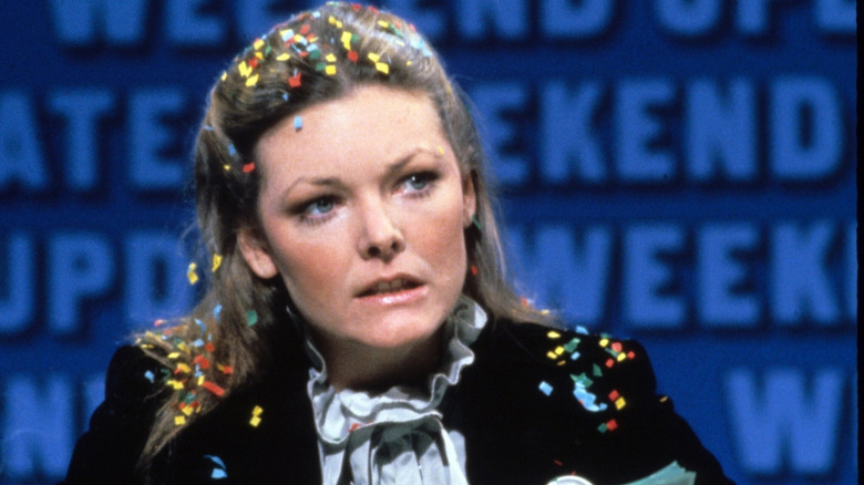Black-and-white Jane Curtin sitting at the Weekend Update desk at SNL