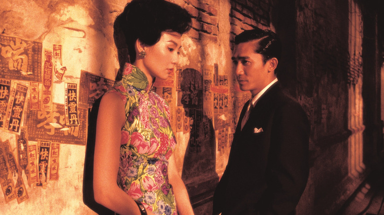 In the Mood for Love, Su Li-zhen looking away in the foreground while Chow in the background watches her