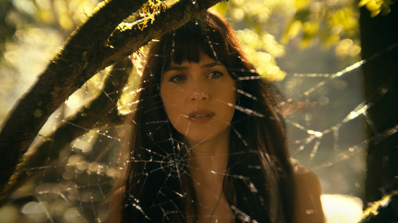 Dakota Johnson as Cassandra Web looking through a spider's web in Madame Web