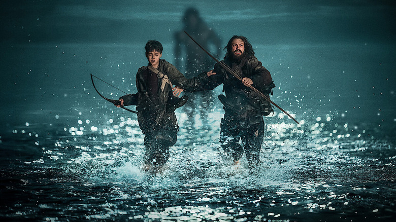 Aaron Taylor-Johnson as Jamie and Alfie Williams as Spike running away from a zombie in the water in 28 Years Later
