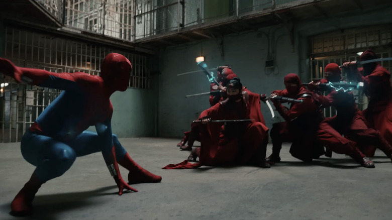Tom Holland as Peter Parker wearing his superhero suit and preparing to fight several ninjas dressed in red in Spider-Man: Brand New Day