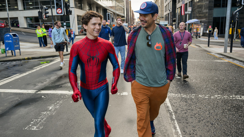 Tom Holland as Peter Parker walking down a street next to director Destin Daniel Cretton on the set of Spider-Man: Brand New Day