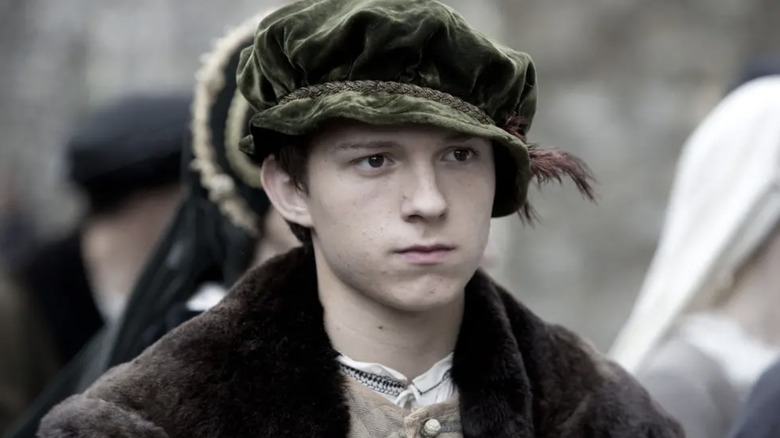 Tom Holland as Gregory Cromwell wearing a green hat in Wolf Hall