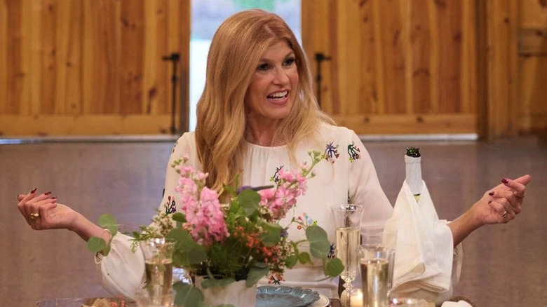 Connie Britton as Nicole smiling at a restaurant table in The White Lotus