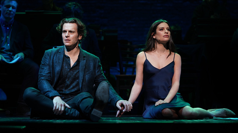 jonathan groff and lea michele sitting on a floor holding hands and looking away from each other in spring awakening