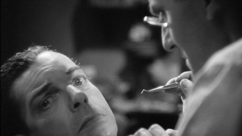 A dentist looming over his patient in The Man Who Knew Too Much