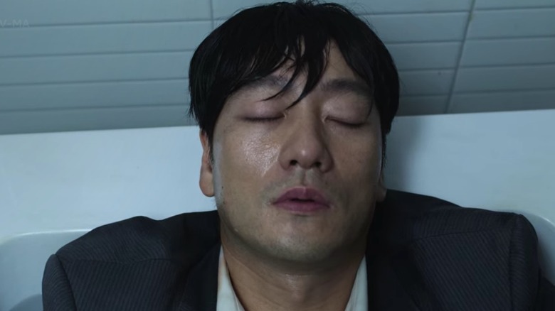 squid game sang-woo lies clothed in bath