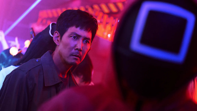 Gi-hun looks shocked and follows a masked guard in Squid Game season 2