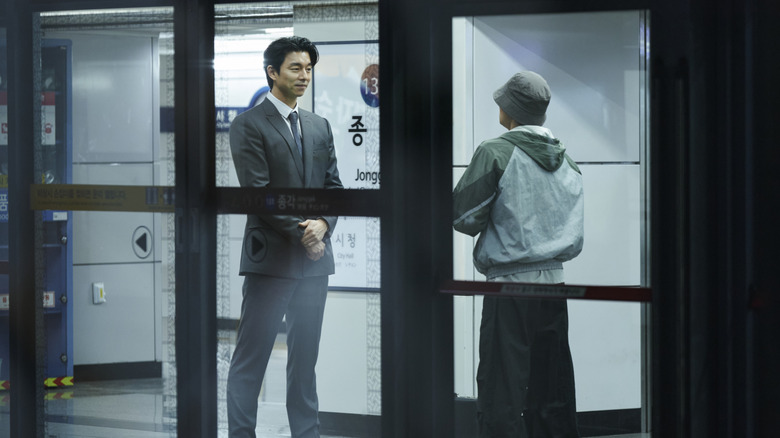 The Recruiter speaking to someone in the subway on Squid Game