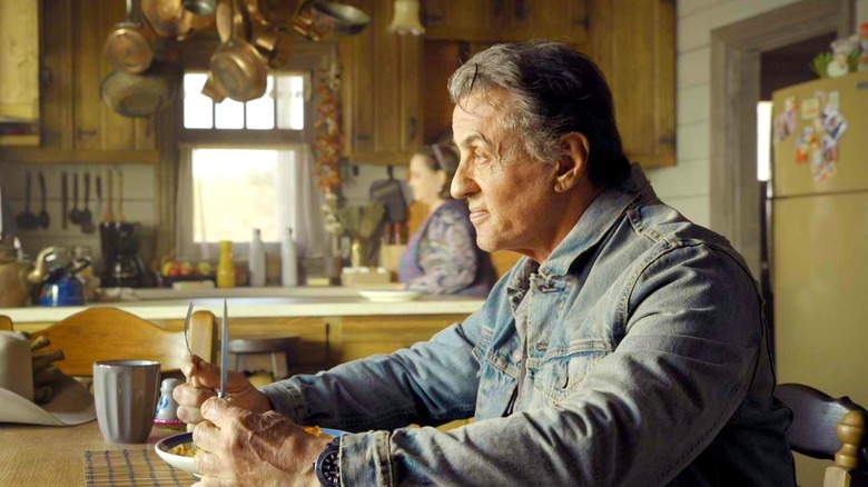 Rambo sitting at a table awaiting his dinner in Rambo: Last Blood