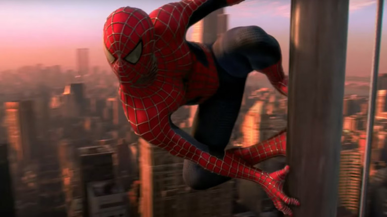 Spider-Man hangs from a flag pole high above Manhattan while wearing his iconic red and blue spidey suit in "Spider-Man"