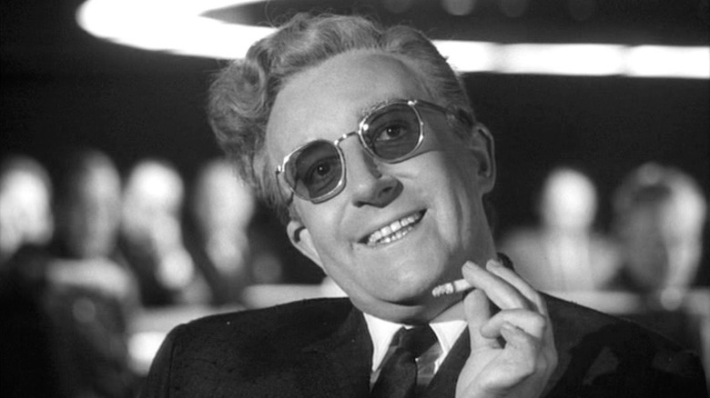 A deranged smiling Dr. Strangelove (Peter Sellers) holds a cigarette in Dr. Strangelove
