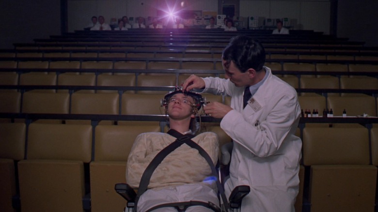 Alex in a big theater, strapped to a chair, next to an ophthamologist in A Clockwork Orange