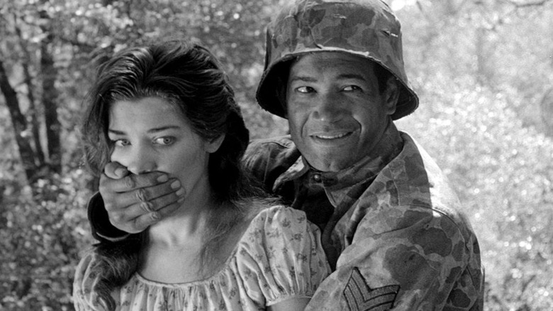 A soldier, holding a woman's mouth, a scene from Fear and Desire.