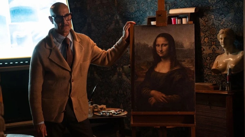 Stanley Tucci as Roger Cavendish stands in front of the Mona Lisa in Masterplan