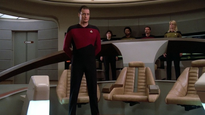 Q in a unform standing on the birdge of the Enterprise in Star Trek: The Next Generation