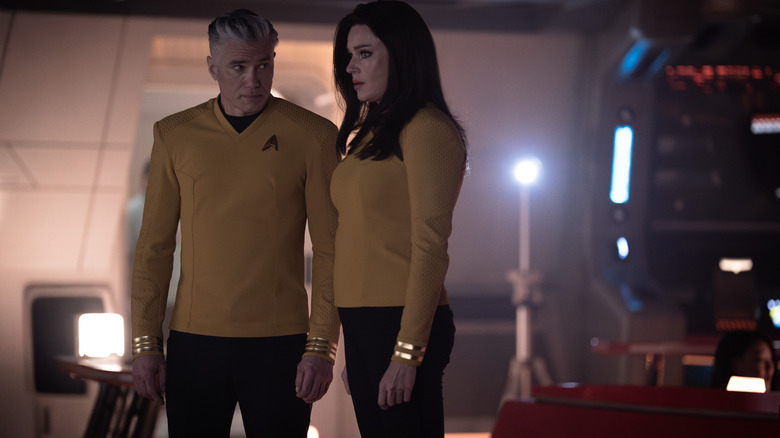 Anson Mount como Capitán Christopher Pike y Rebecca Romijn como Una Chin-Riley de pie en el puente de la empresa del USS en extraños nuevos mundos