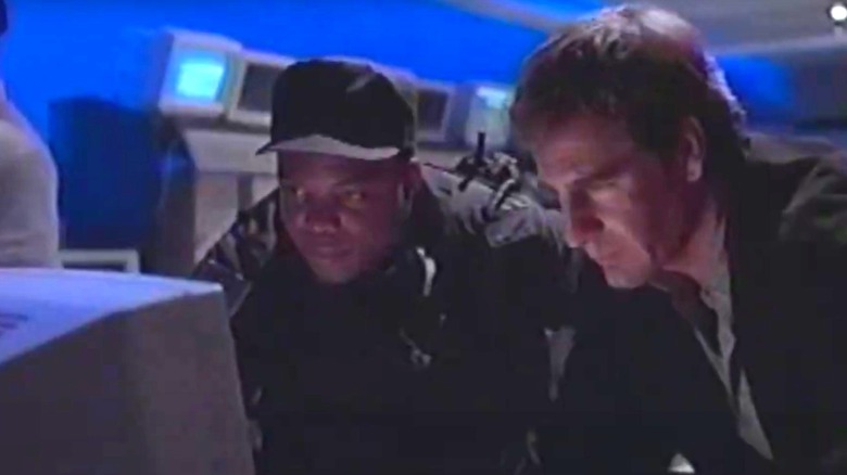 Alex Michaels dari Scott Bakula terlihat serius dan menatap layar komputer di NetForce
