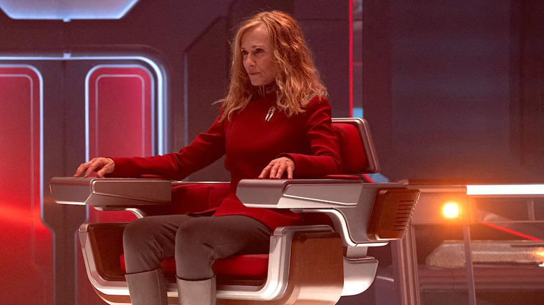 Captain Nahla Ake sits in her captain's chair, sternly weighing her options while dressed in her red officer's uniform in "Star Trek: Starfleet Academy"