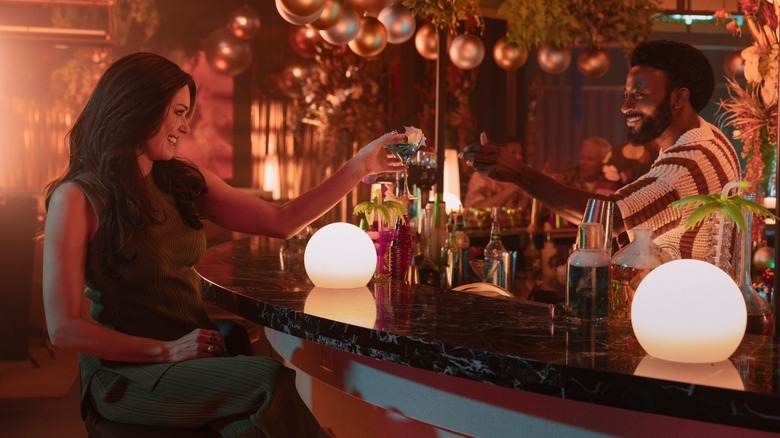 Commander Chin-Riley being handed a drink across a bar by Dr. M'Benga on Star Trek: Strange New Worlds