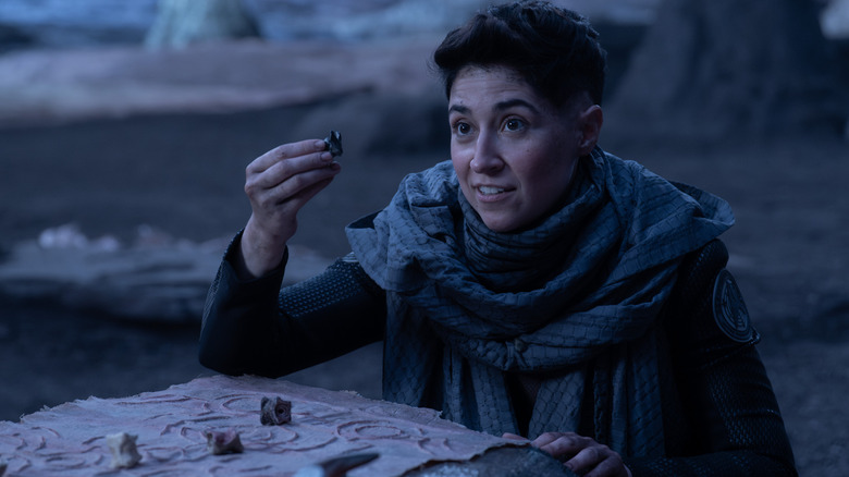 Melissa Navia as Ortegas in Star Trek: Strange New Worlds, holding up a game piece on a deserted planet