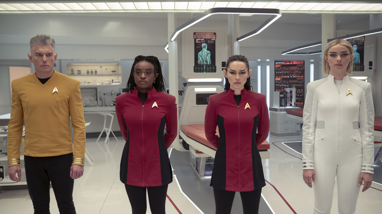 Anson Mount as Christopher Pike, Celia Rose Gooding as Uhura, Christina Chong as La'an, and Jess Bush as Nurse Chapel all standing side-by-side and sporting Vulcan ears and eyebrows in Star Trek: Strange New Worlds