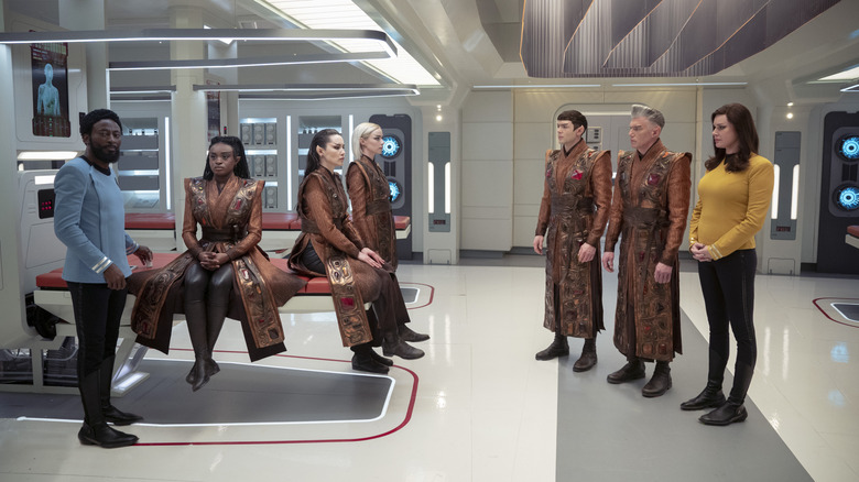 Babs Olusanmokun as Dr. M'Benga and Rebecca Romijn as Una standing beside Celia Rose Gooding as Uhura, Christina Chong as La'an, Jess Bush as Nurse Chapel, Ethan Peck as Spock, and Anson Mount as Pike dressed in Vulcan garb in Star Trek: Strange New Worlds