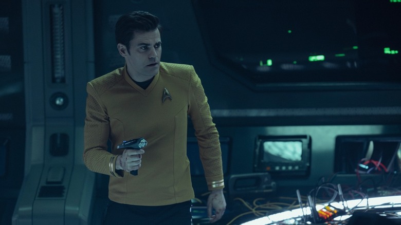 Kirk with a phaser on a darkened starship on Star Trek: Strange New Worlds