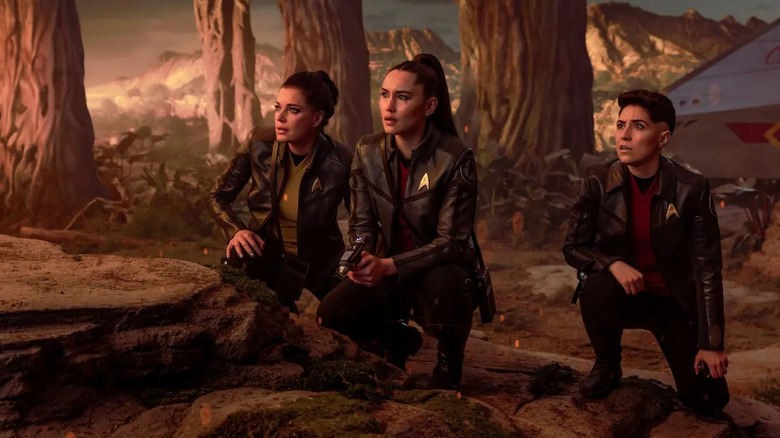 the Enterprise crew, crouched and looking worried on an alien planet on Star Trek: Strange New Worlds