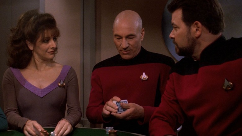 Picard, sitting in between Troi and Riker at a card table, shuffling a deck. From Star Trek: The Next Generation.