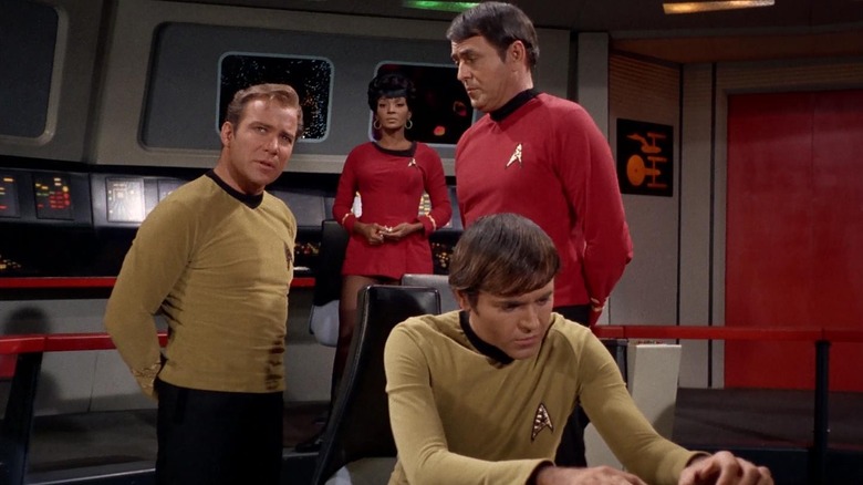 Kirk, Uhura, Scotty, and Chekov on the bridge of the Enterprise on Star Trek
