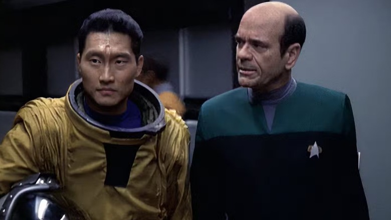 Gotana-Retz (Daniel Dae Kim) in an astronaut outfit walks beside the Doctor (Robert Picardo) in Star Trek: Voyager