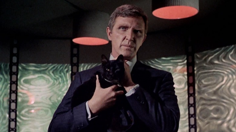 Gary Seven standing on the transporter pad, holding a black cat. A scene from Star Trek.